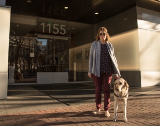 Access Technology director Erin Lauridsen standing outside LightHouse headquarters with her guide dog Kendall