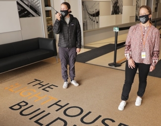 Two people wearing masks standing six feet apart in the LightHouse building lobby at 1155 Market Street