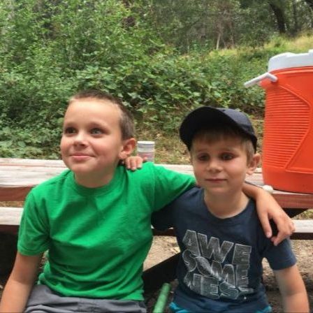 Two kids sit on a bench and smile at EHC