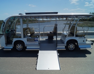 A white electric shuttle bus with wheelchair ramp extended