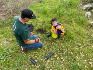 Two volunteers, a man and a child, planting a tree at Enchanted Hills Camp in Napa