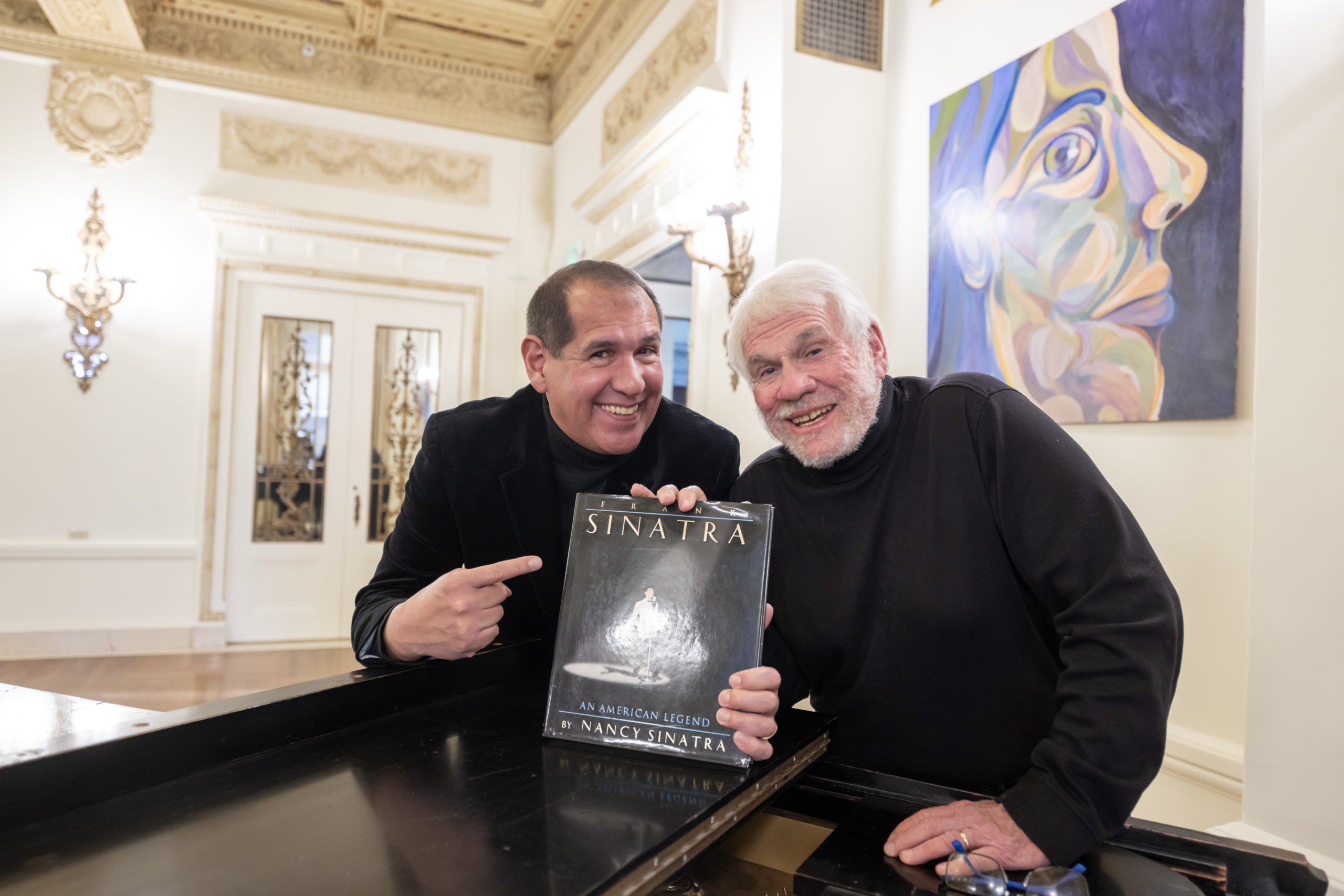 Alex and Steve smile and hold the book, Frank Sinatra: An American Legend by Nancy Sinatra. 