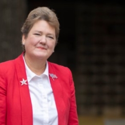 Sharon Giovinazzo in a dark pink suit with a white blouse