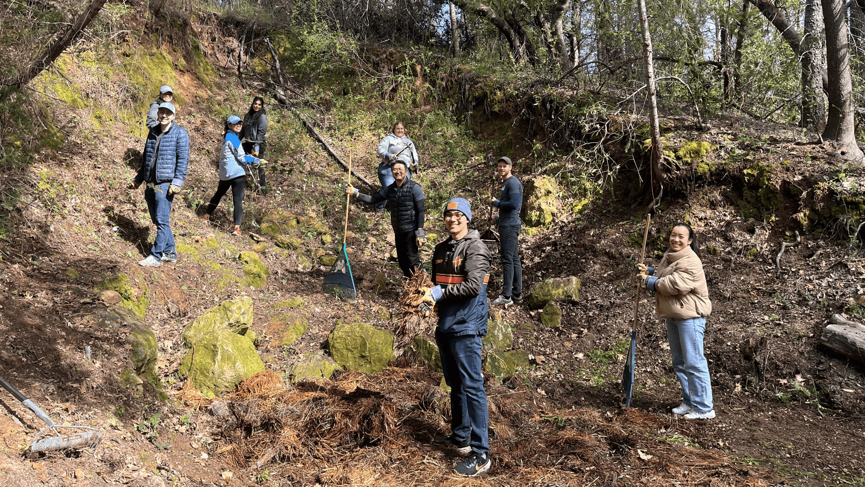 Federal Reserve Bank employees take a break from clearing the archery range at EHC to turn towards the camera and smile.