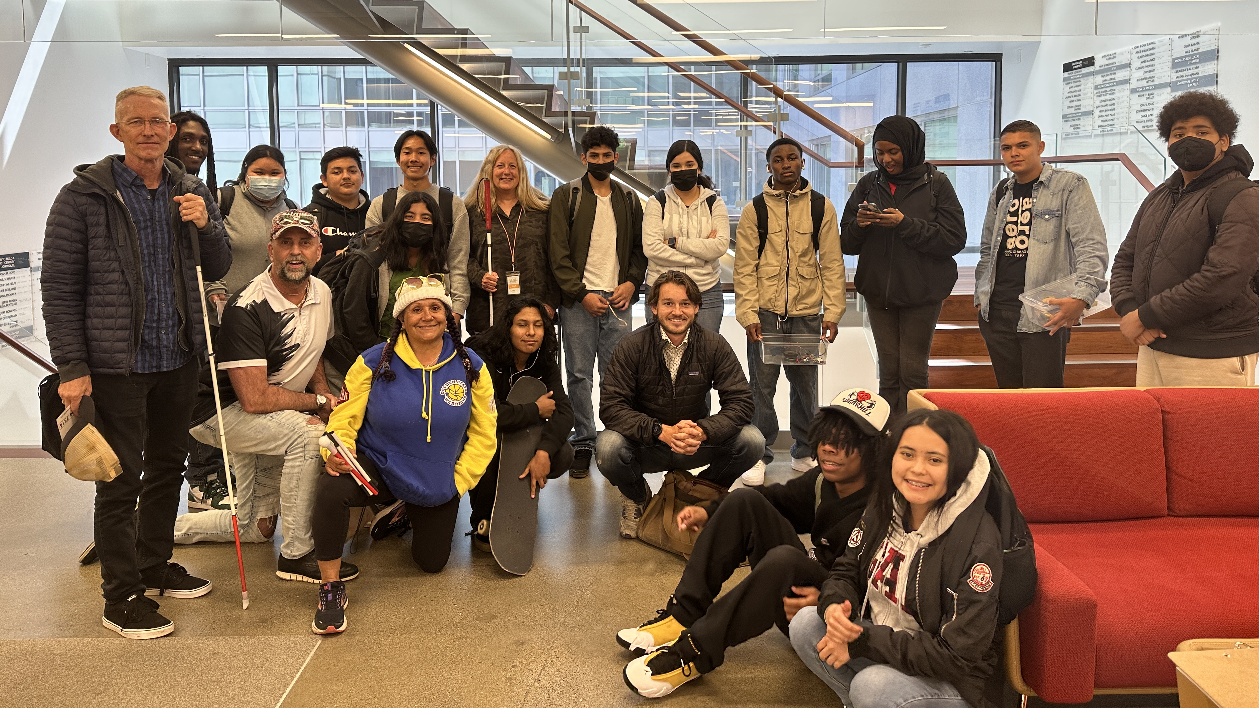 Latitude students and instructor pose with LightHouse community members and staff in front of the 10th floor staircase at LightHouse in 2023.