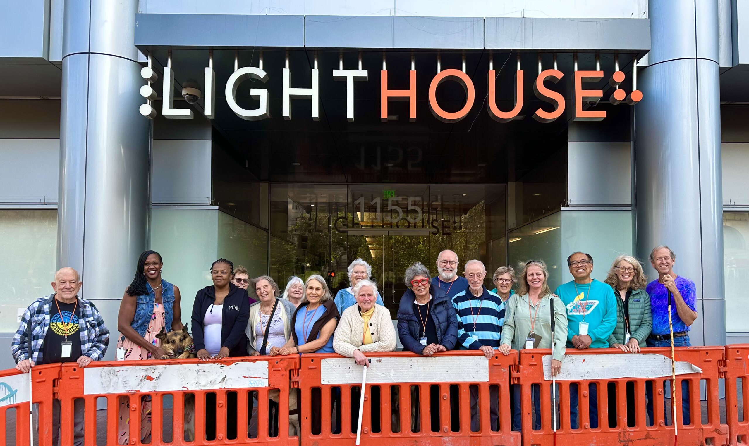 The June 2023 CVCL students and staff stand outside LightHouse headquarters. They are lined up behind an orange barricade