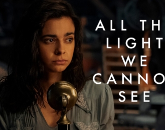 A teenage girl, Marie-Laure Leblanc, sits in front of a old time radio microphone