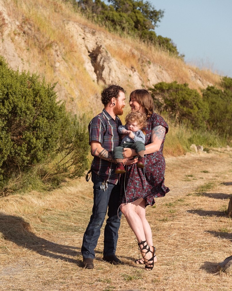 Mom and Dad hold their Little Learner, Ottis, as they pose for a family portrait in a park