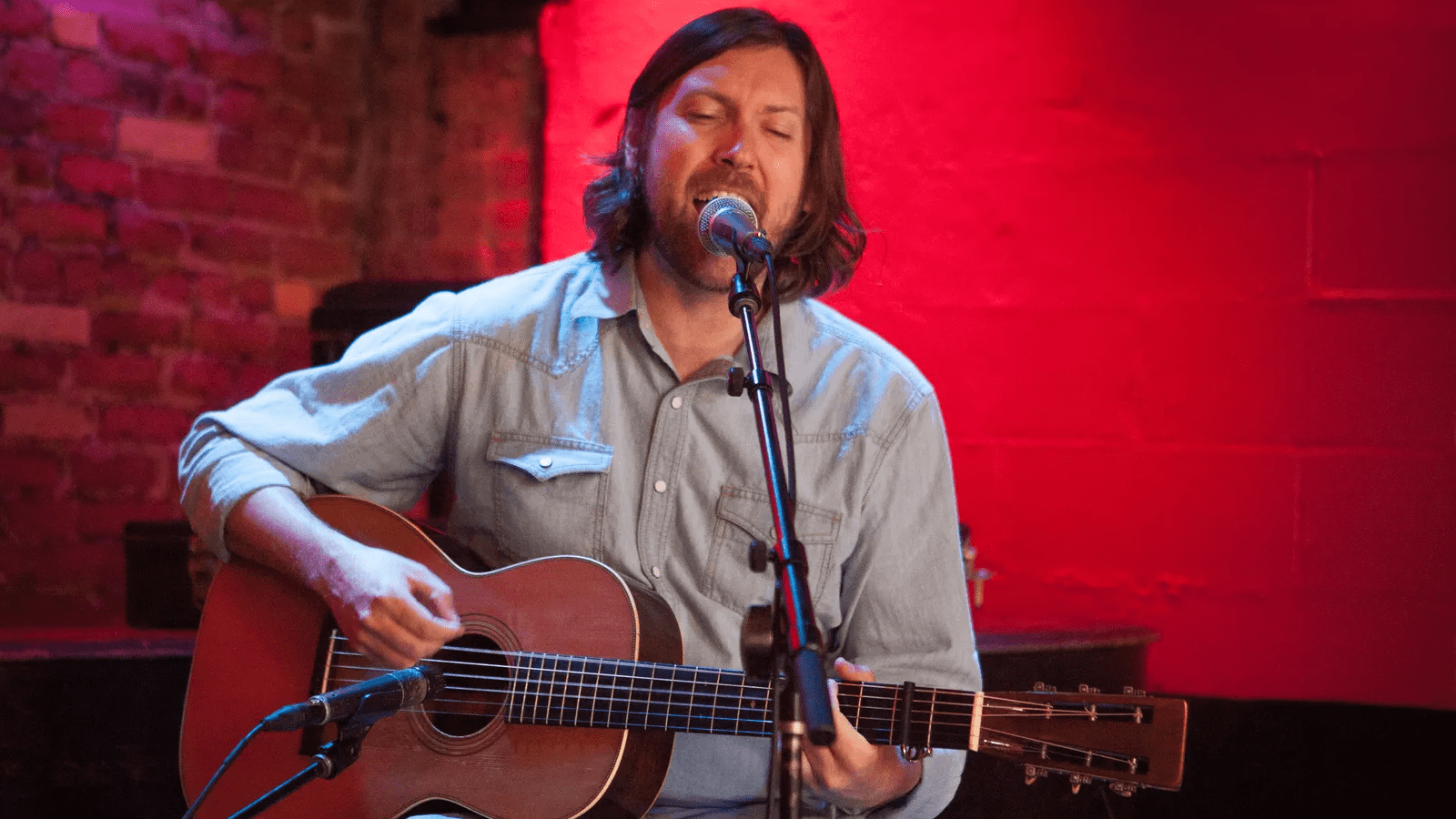 Graham Norwood singing while playing guitar