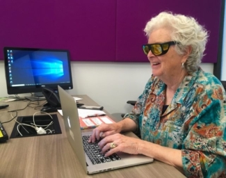 A student wearing yellow fitover sunglasses types at a laptop in a LightHouse tech lab