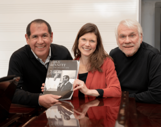 Alex Perez, Marie Finch and Steve Gill pose together holing a book about Tony Bennett
