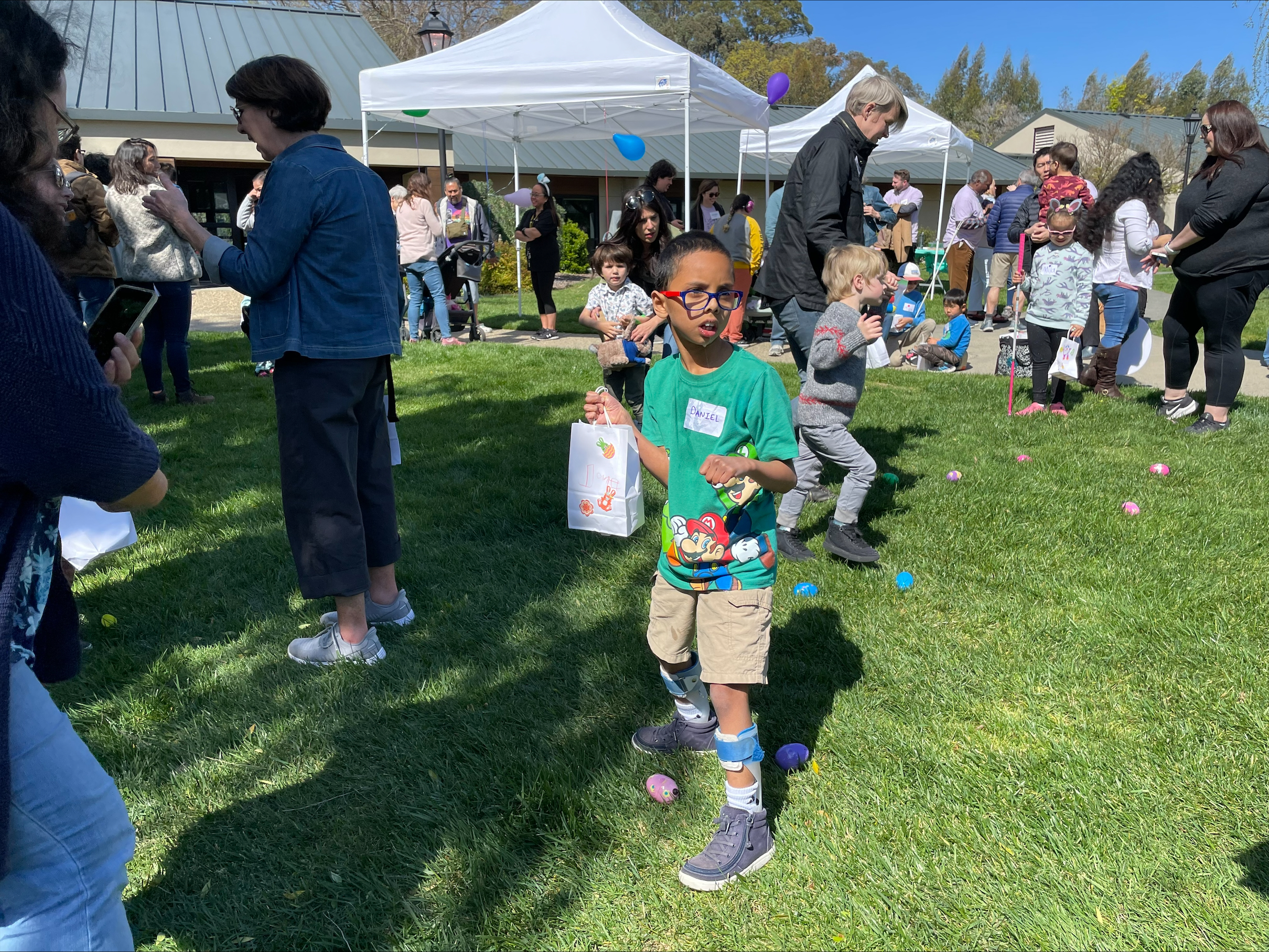 LightHouse Little Learners holding spring-themed decorated bags hunt for beeping eggs at an accessible egg hunt at last year's Spring Celebration