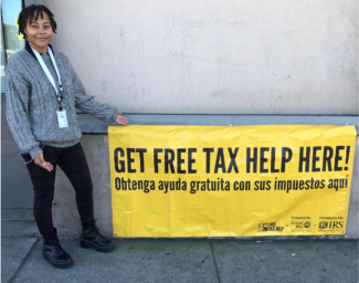 A person holding a sign that reads get your free tax help here!
